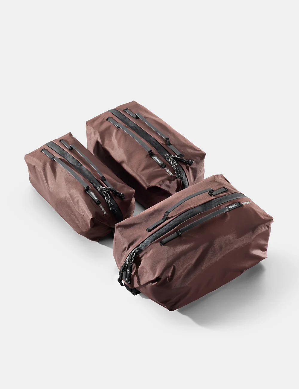 Three brown travel bags with zippers on a light gray background