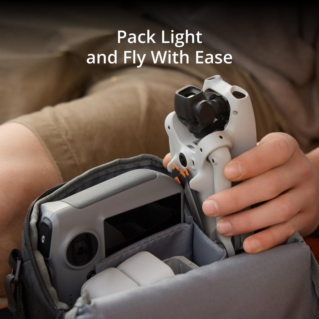 Hand holding a drone controller with text 'Pack Light and Fly With Ease' over a blurred background