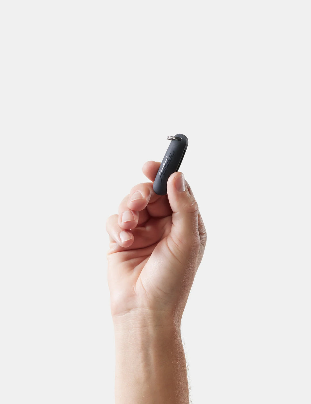 Hand holding a small black matador earplugs kit against a light background