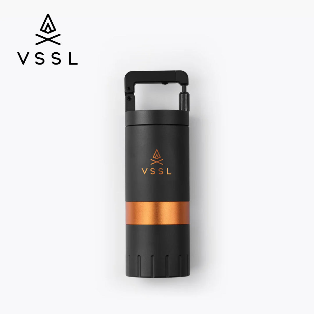 A VSSL Coffee Grinder black with a metallic copper band around the middle and a matching VSSL logo on the front, shown on a clean white background with a VSSL logo in the top-left corner.