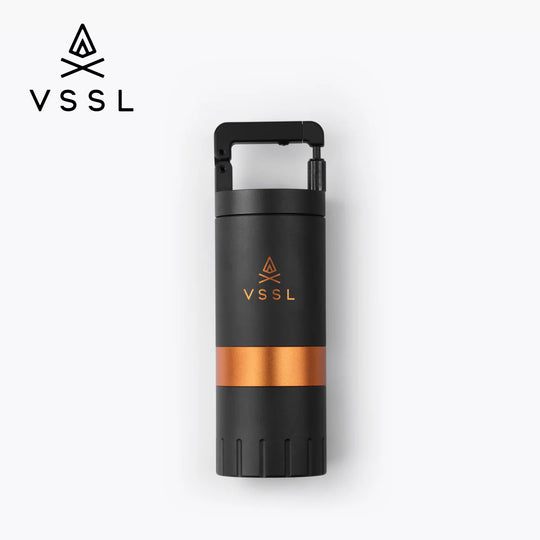 A VSSL Coffee Grinder black with a metallic copper band around the middle and a matching VSSL logo on the front, shown on a clean white background with a VSSL logo in the top-left corner.