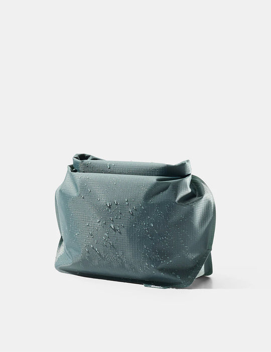 Teal fabric bag with water droplets on a light gray background