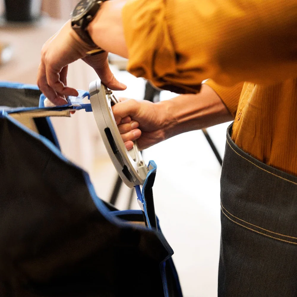 Person wearing a yellow shirt and blue apron working on a softbox.