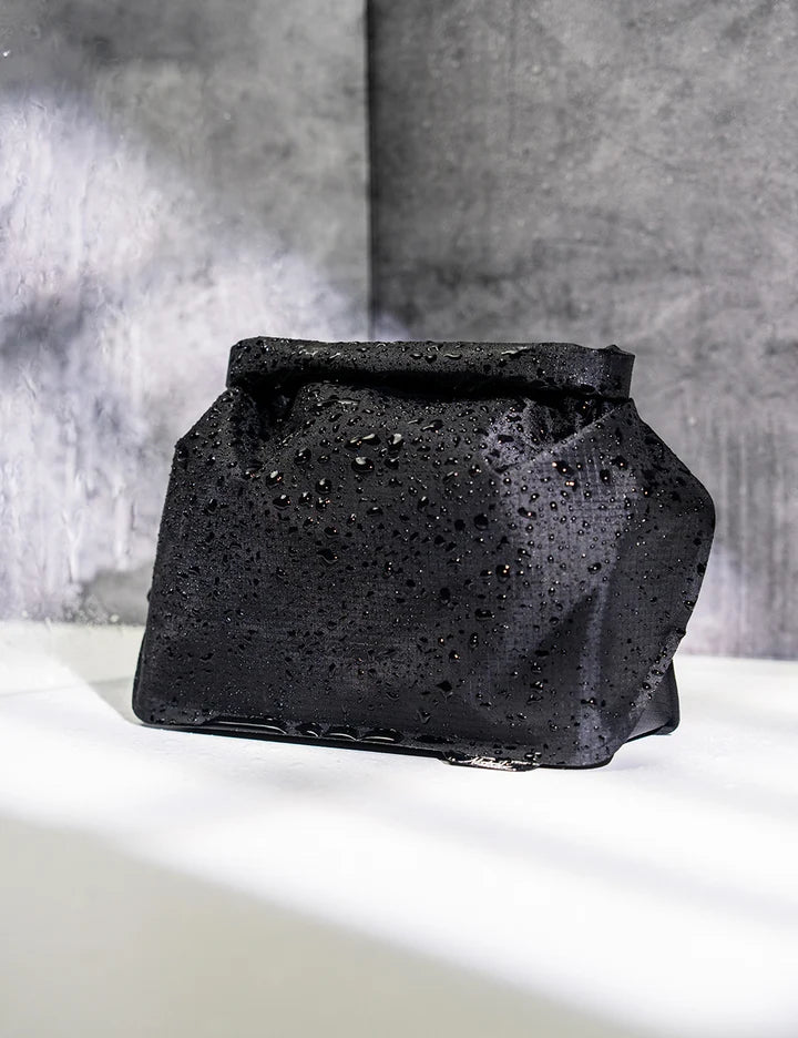Black soap bar with water droplets on a white surface and gray background