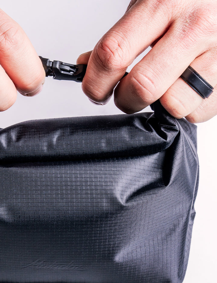 Person opening a gray bag with a zipper