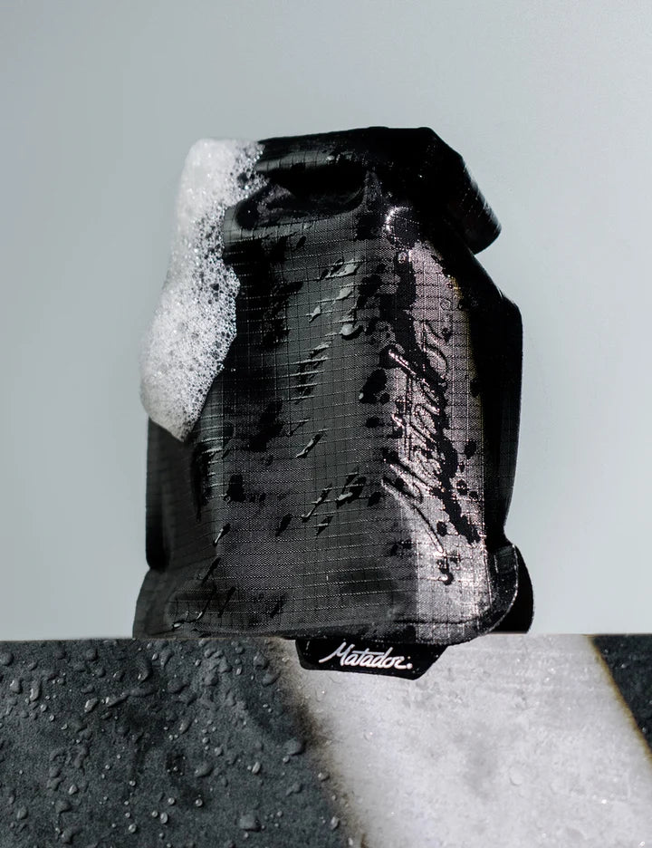Black soap bar with lather on a gray background