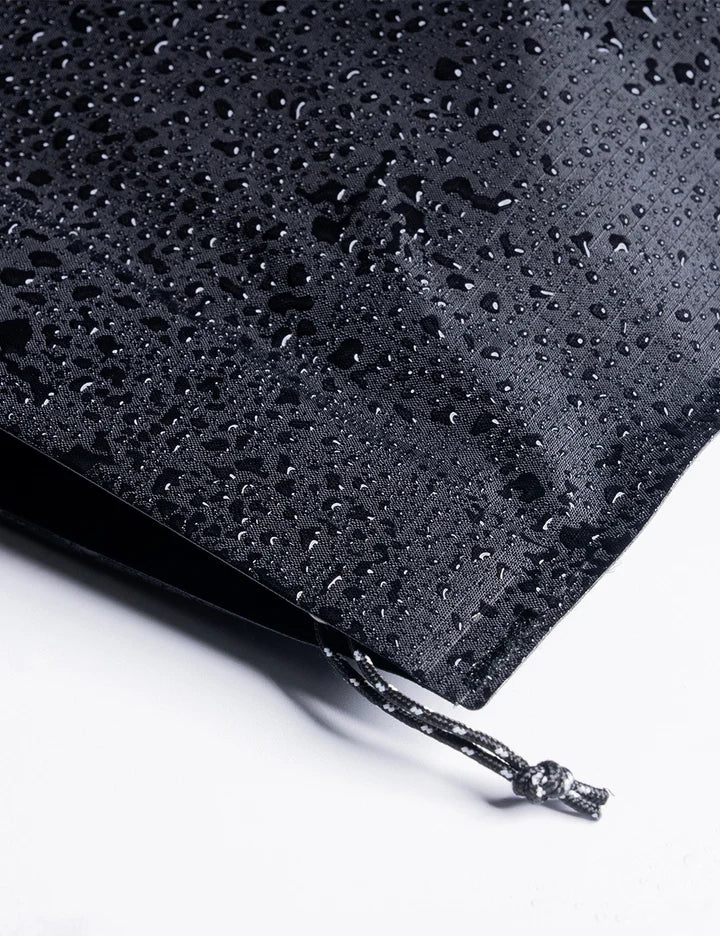 Black drawstring bag with water droplets on a white background