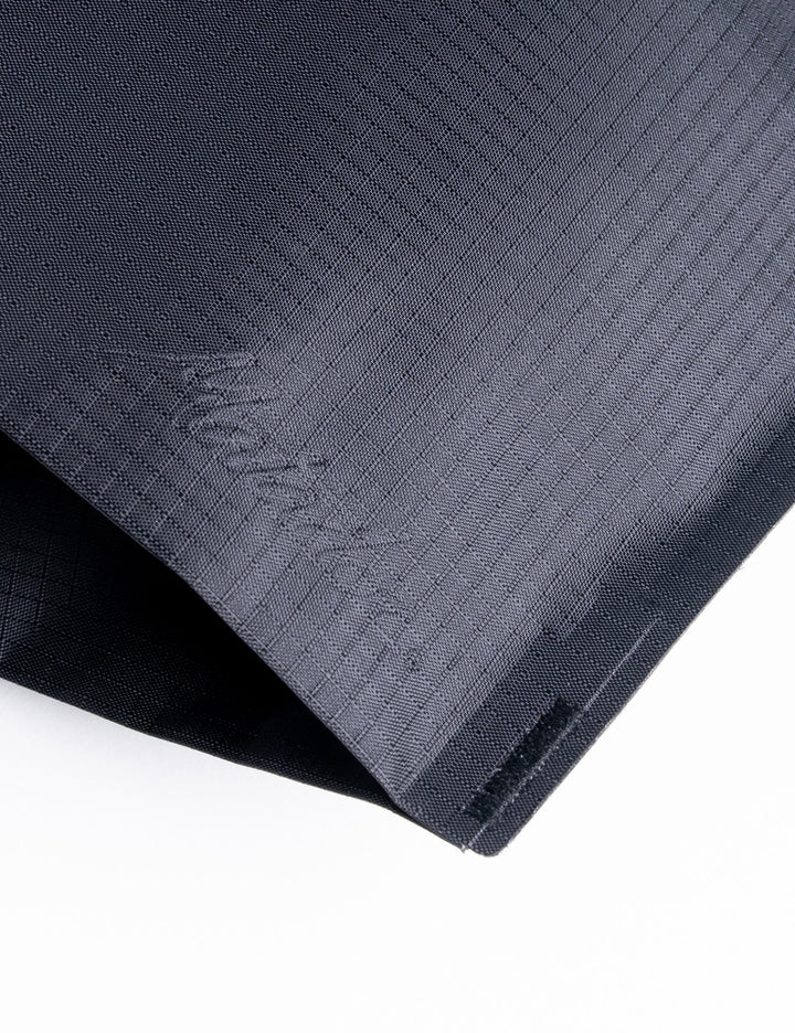 A close-up of a dark gray textured fabric, likely a towel or mat, folded over on a white background. The brand name 'Kings of NY' is subtly embossed on the fabric.