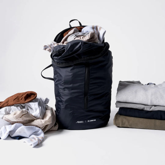 Black laundry bag with clothes on a white background