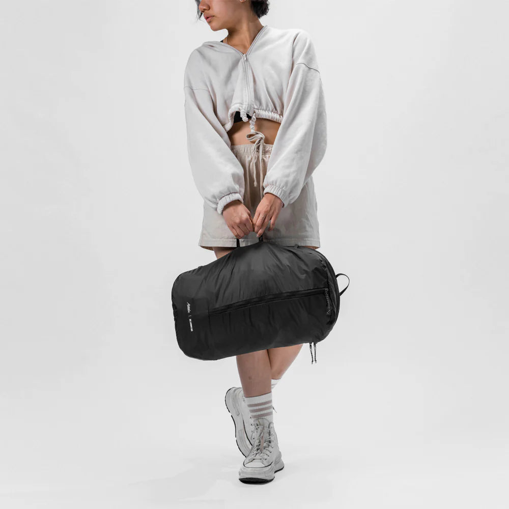 Person holding a black Packable Laundry Bag against a white background