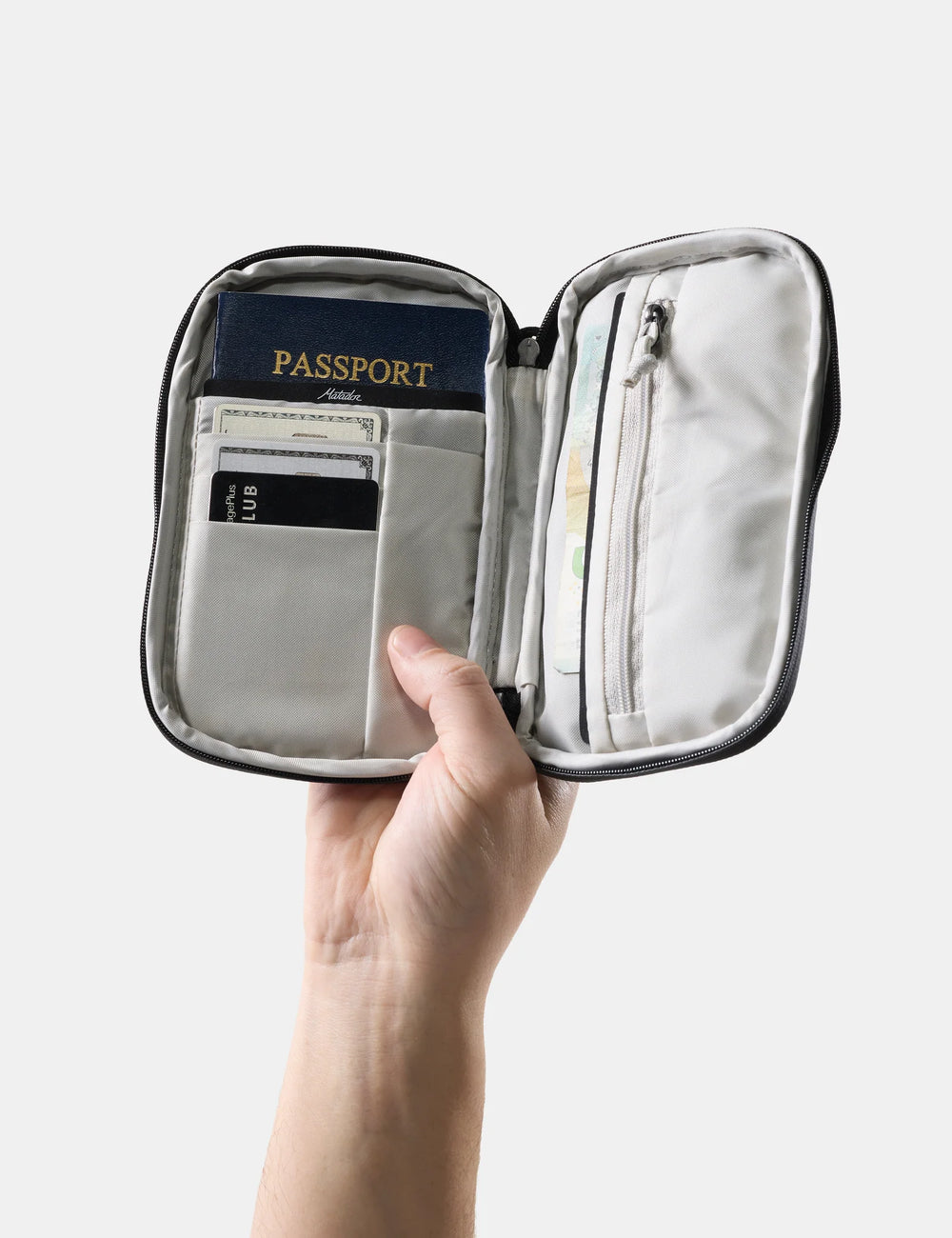 Hand holding an open travel organizer with a passport and cards on a light gray background