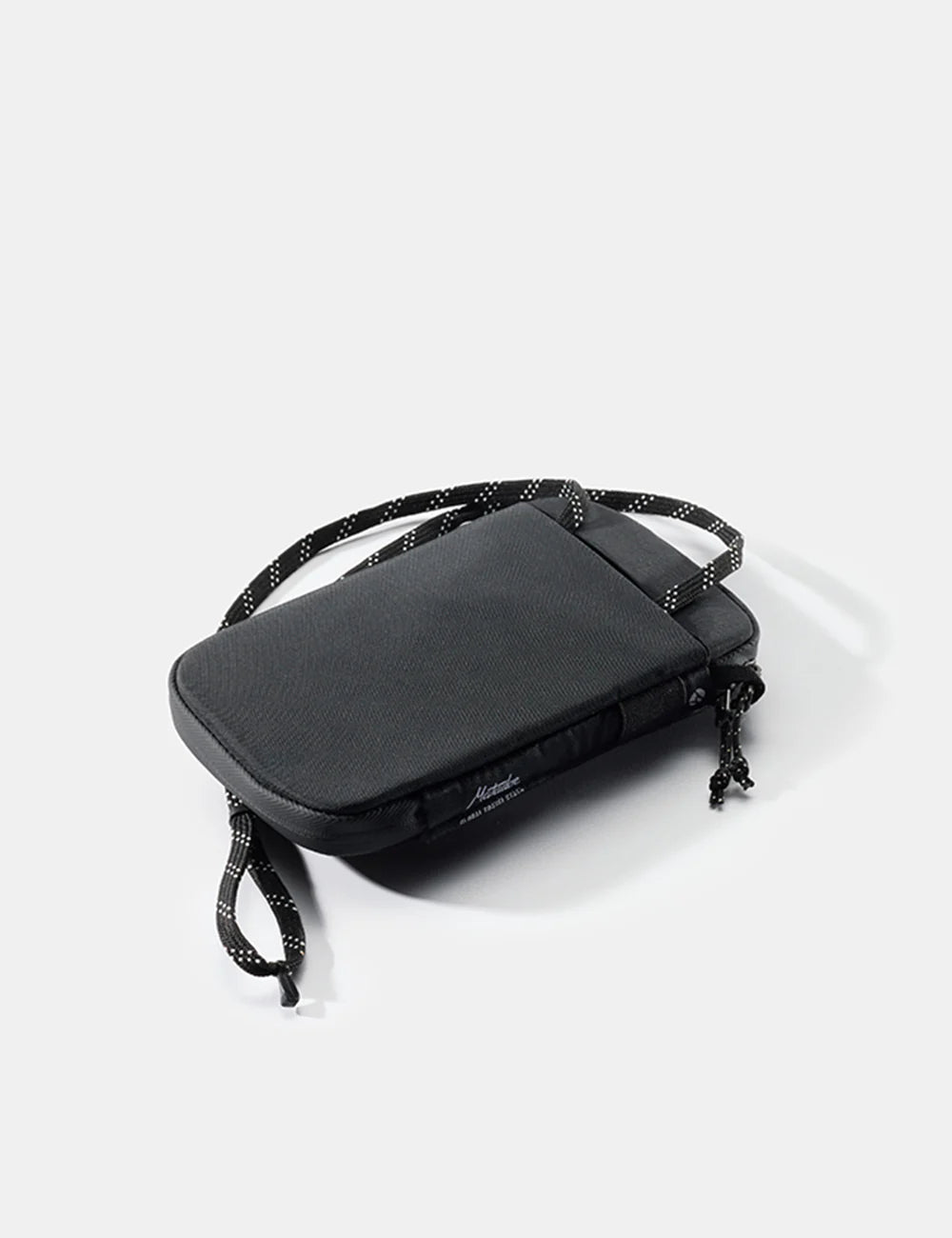 Black crossbody Global Travel Stash with adjustable strap on a light gray background