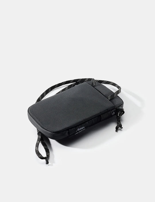Black crossbody Global Travel Stash with adjustable strap on a light gray background