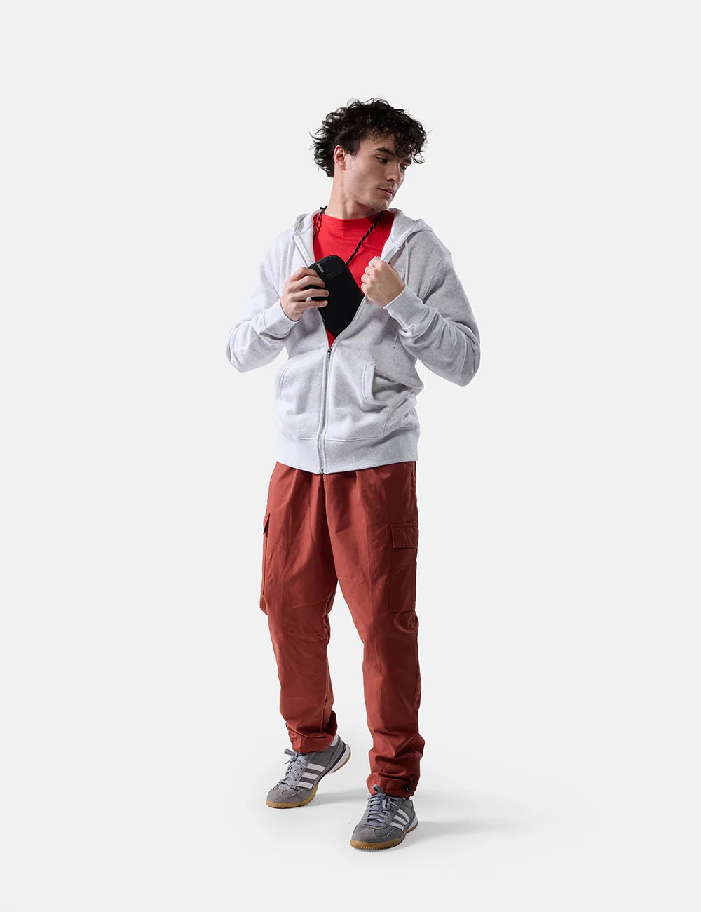 Person wearing a gray hoodie and red pants holding a Global Travel Stash on a white background