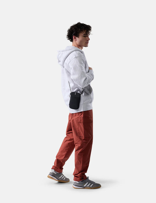 Person wearing a gray hoodie and red pants standing against a white background
