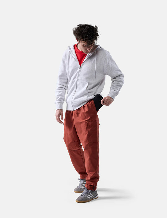Person wearing a gray hoodie and red pants on a white background