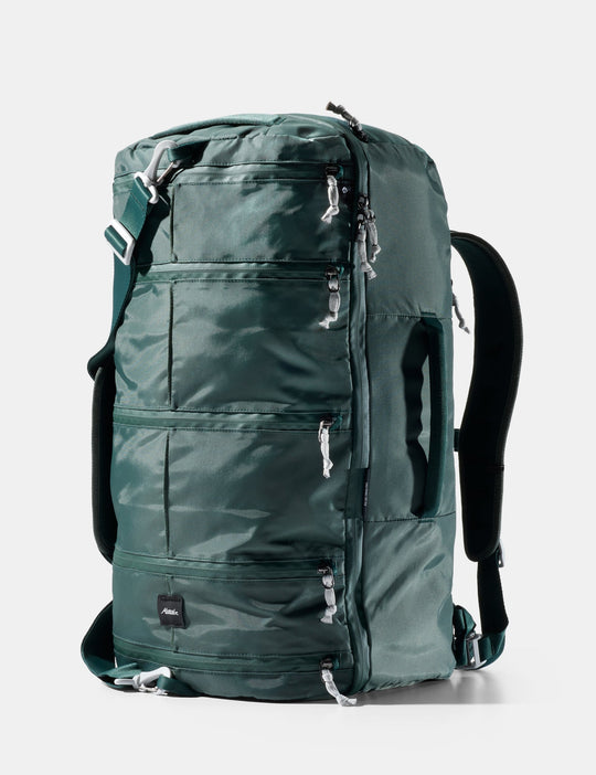 Green backpack with multiple zippers on a white background