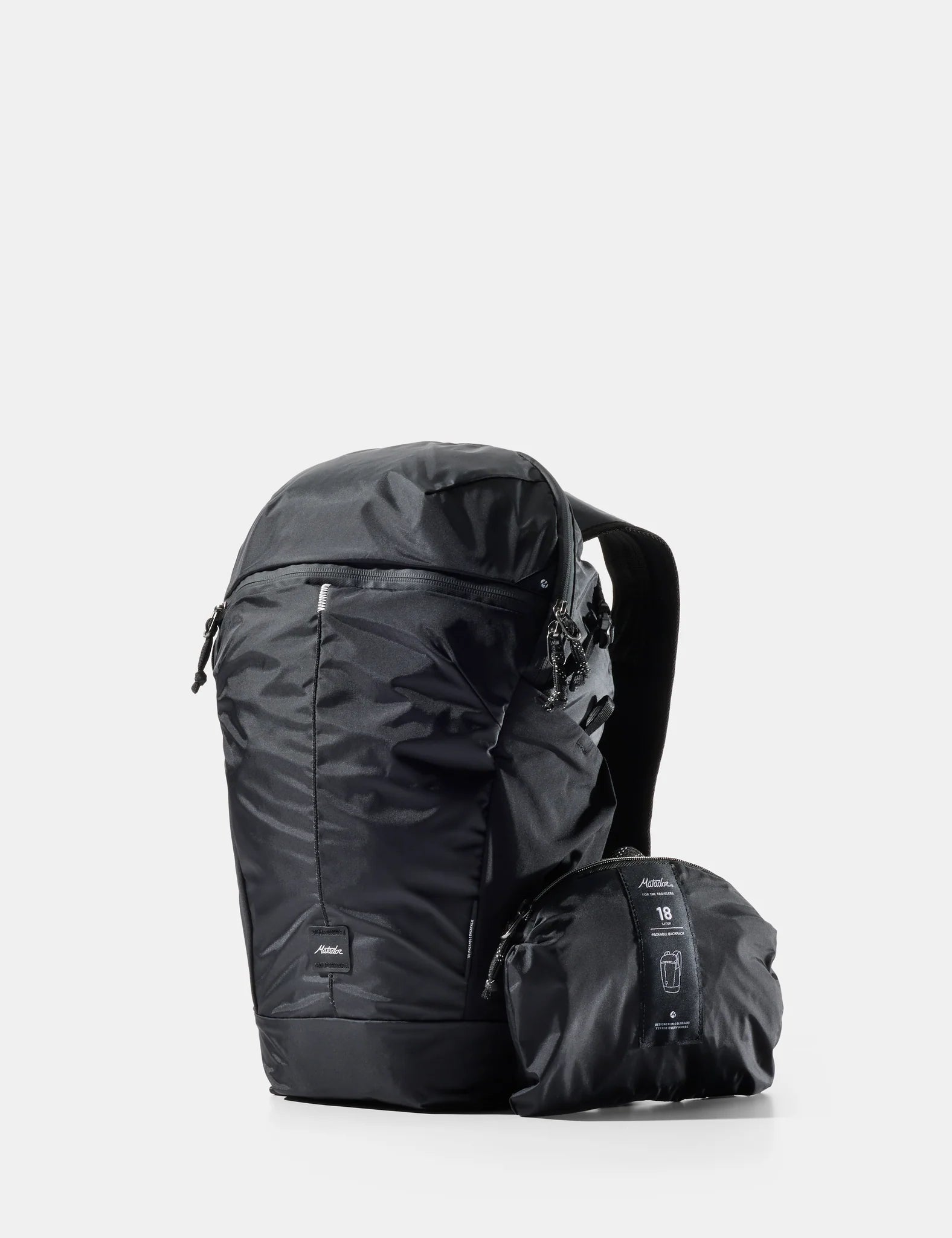 Matador 18L packable backpack shown in black on a light gray background, with the brand name 'Matador' above and the text '18L Packable Backpack' below. A smaller packed version is shown beside the unpacked backpack.