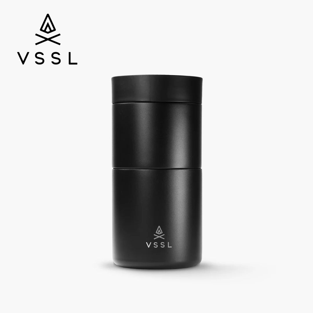 A matte black VSSL travel tumbler with a matching lid, shown on a clean white background with the VSSL logo in the top-left corner.
