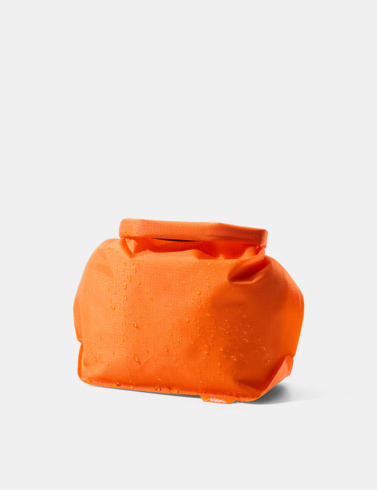 Orange waterproof bag on a light gray background