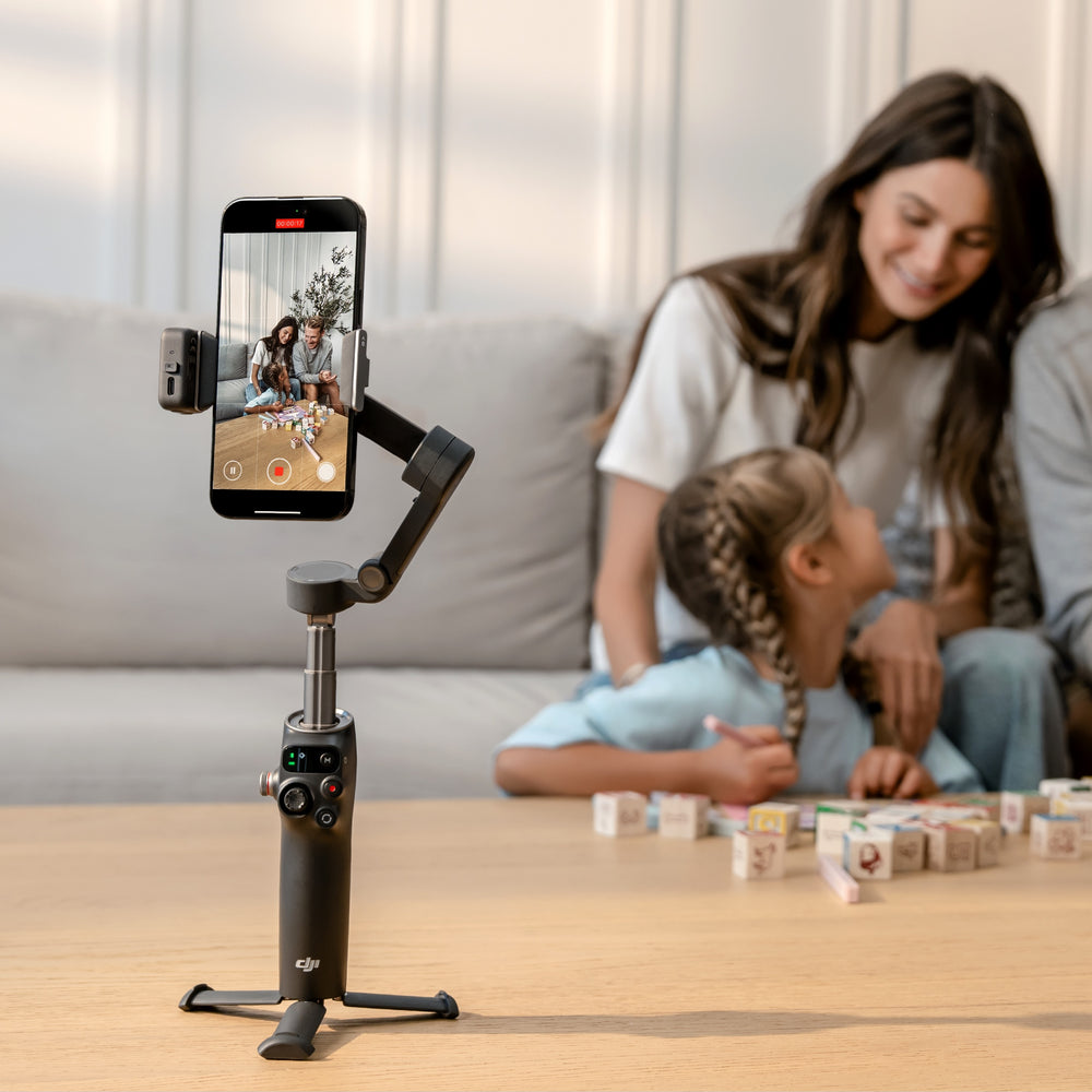 Smartphone mounted on a gimbal with a woman and child playing in the background