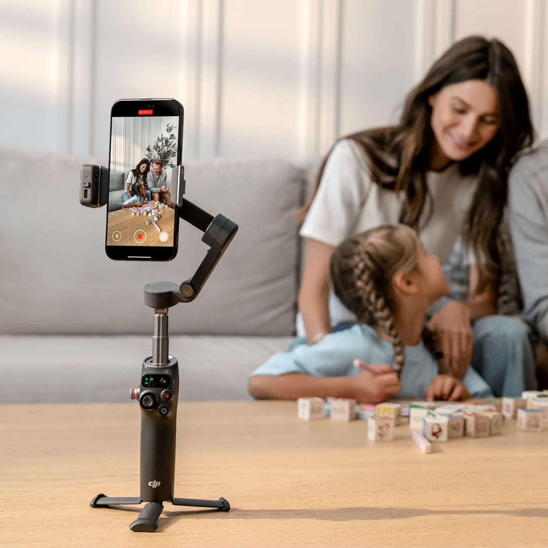 Smartphone mounted on a gimbal with a woman and child playing in the background