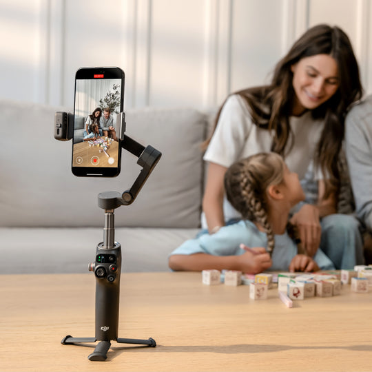 Smartphone mounted on a gimbal with a woman and child playing in the background
