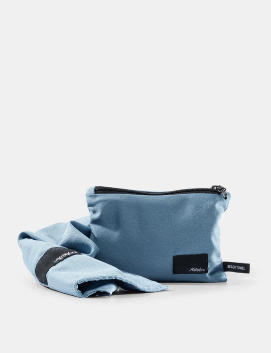Blue pouch and towel set with a matador brand logo on a light gray background