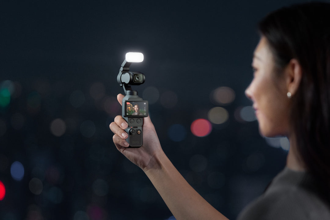Person holding a dji osmo pocket 4 with a fill light on a dark background