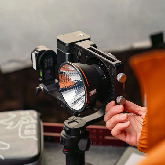 Person adjusting a camera light on a tripod with a blurred background