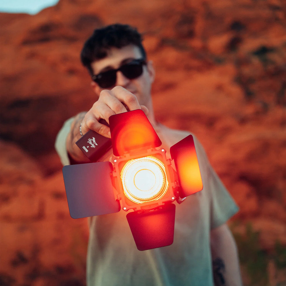 Person holding a red light-emitting device against a blurred natural background