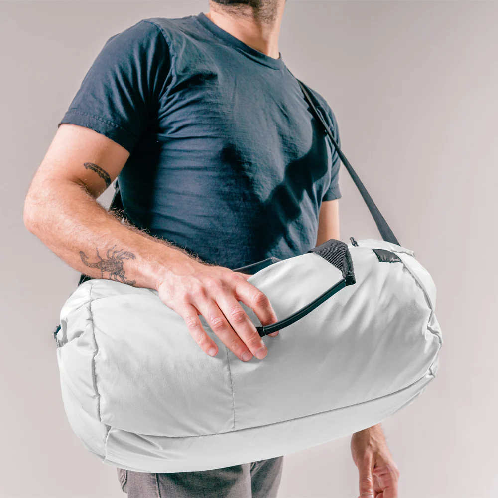 A male model carring white Matador ReFraction Packable Duffle bag
