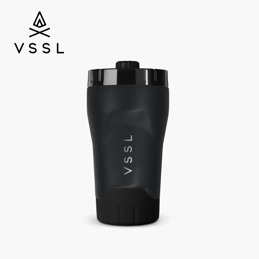 A black VSSL insulated travel tumbler with a matching black lid, shown on a light gray background with the VSSL logo in the top-left corner.