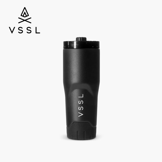 A matte black VSSL travel tumbler with a matching black lid, shown on a light gray background with the VSSL logo in the top-left corner.