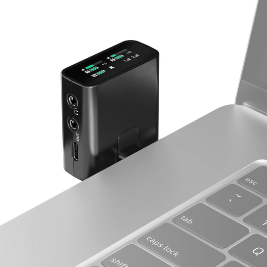 Black electronic device with digital display attached to a laptop on a white background