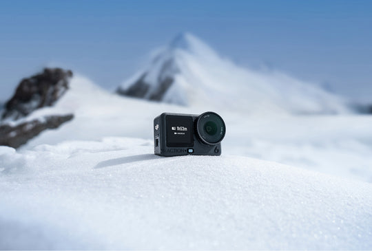 Action camera on a snowy surface with mountains in the background