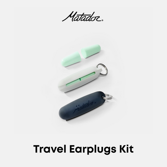 Matador Travel Earplugs Kit featuring three earplugs in mint green, white, and dark navy blue, arranged on a light gray background with the Matador logo at the top and &