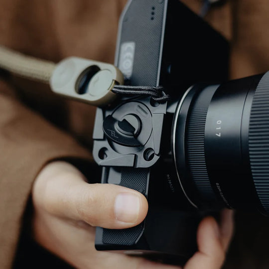 Close-up of a person holding a camera with a lens and strap.