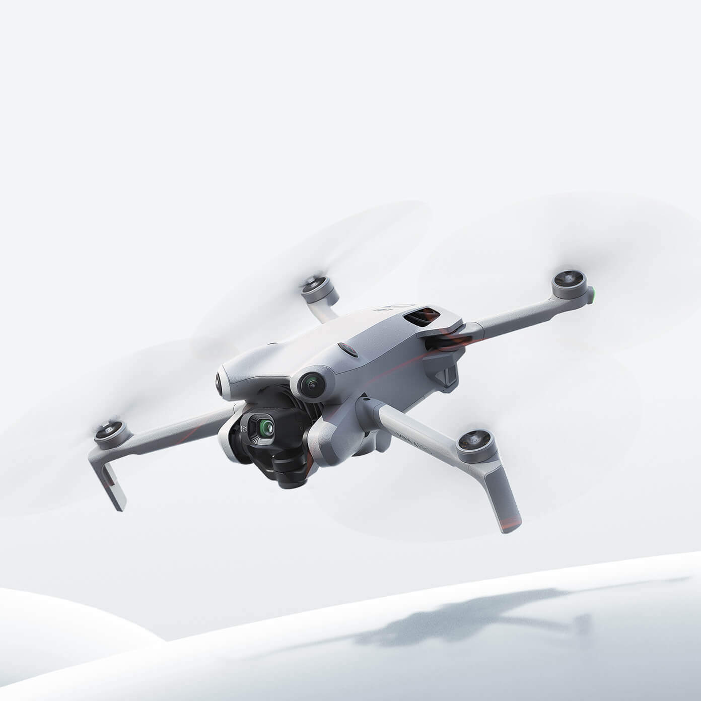 A white DJI Mini 4 Pro drone is shown flying against a light grey and white background, with its propellers blurred from motion. The text 