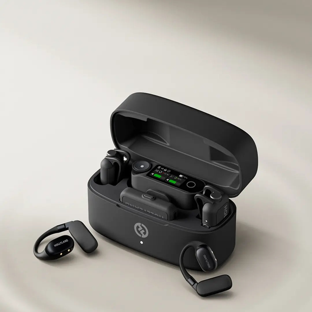 A collection of HollyLand Lark M2 wireless microphone components is displayed on a white surface against a light background. In the center, an open charging case reveals empty slots. Around it are several small, black microphone units with the HollyLand logo, some appearing to float, and two different types of receivers (one with a USB-C connector). The text 