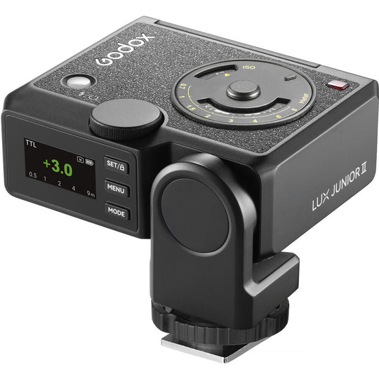Three-quarter perspective view of the Godox Lux Junior II Retro Camera Flash highlighting the digital rear display screen, side control buttons, tilt pivot mechanism, top analog calculation dial, and hot shoe mount foot.
