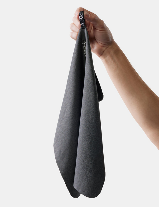 Person holding a gray towel with a brand logo on a white background