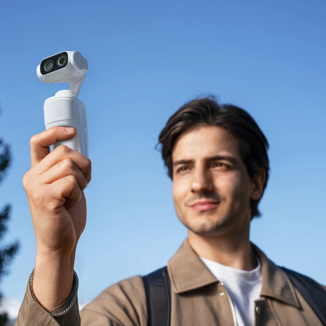 Man holding an Insta360 Luna Ultra gimbal camera fitted with the white Sliding Protective Case while recording outdoors against a clear blue sky.