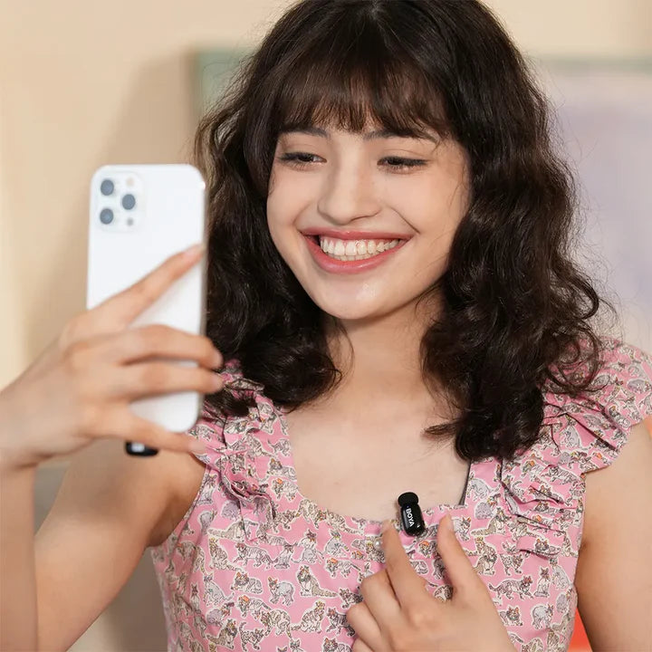 Woman taking a selfie with a phone, wearing a pink floral dress.