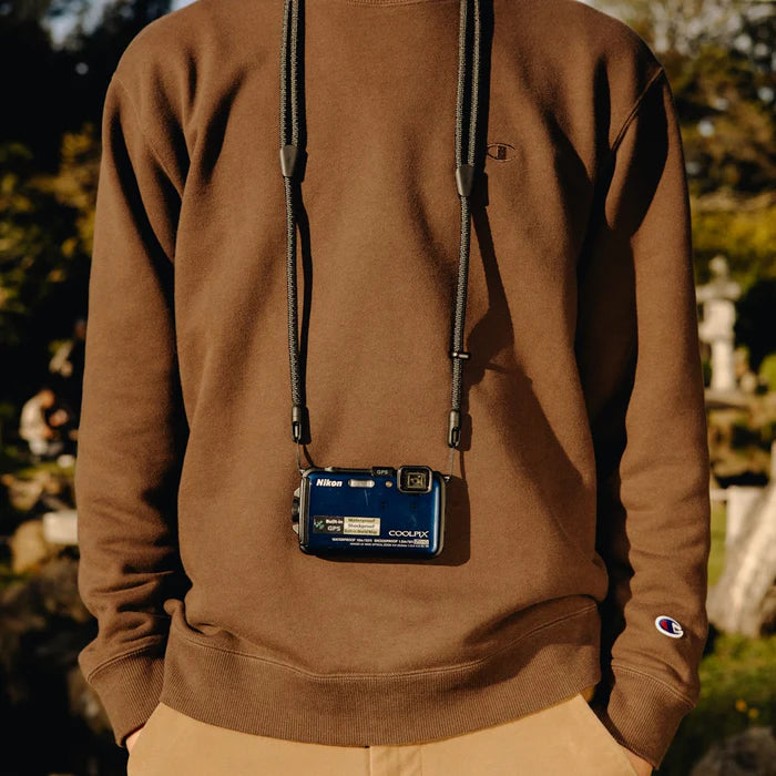 medium shot of a person wearing peak design black mobile crossbody strap