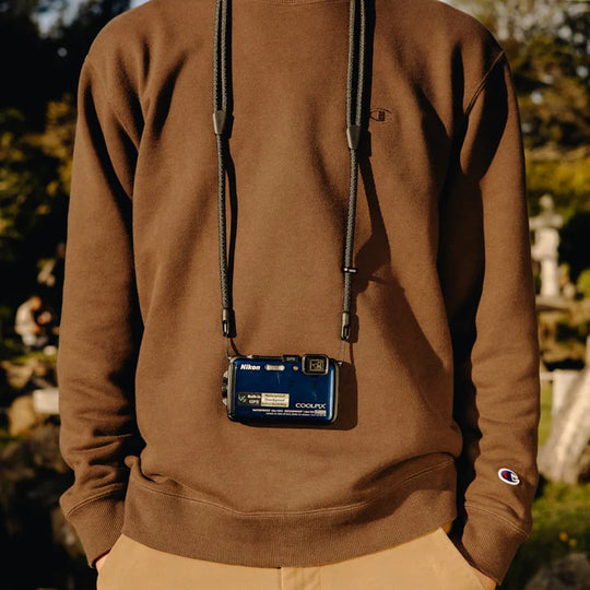 medium shot of a person wearing peak design black mobile crossbody strap