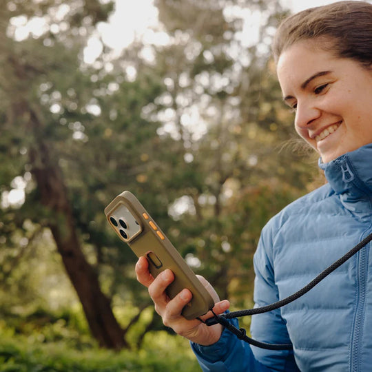 Person holding a phone with a case outdoors