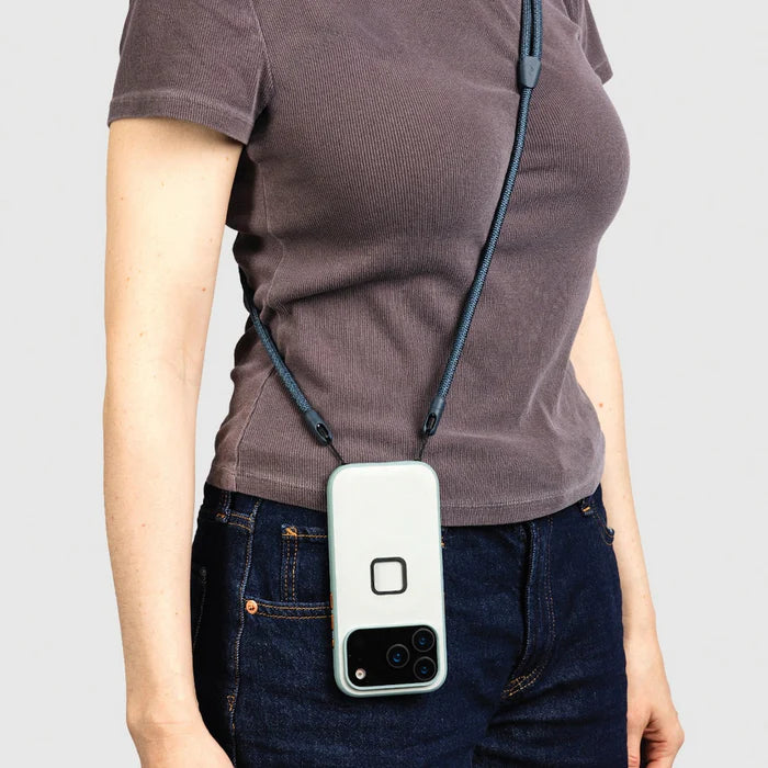 Person wearing a crossbody phone case with a smartphone attached on a plain background
