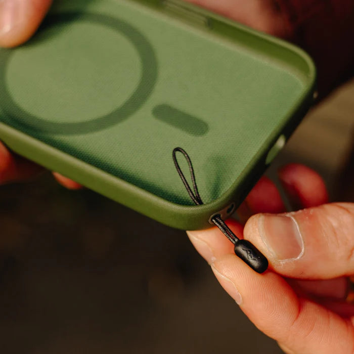 a hand attaching peak design mobile straps microanchor to a green phone case.