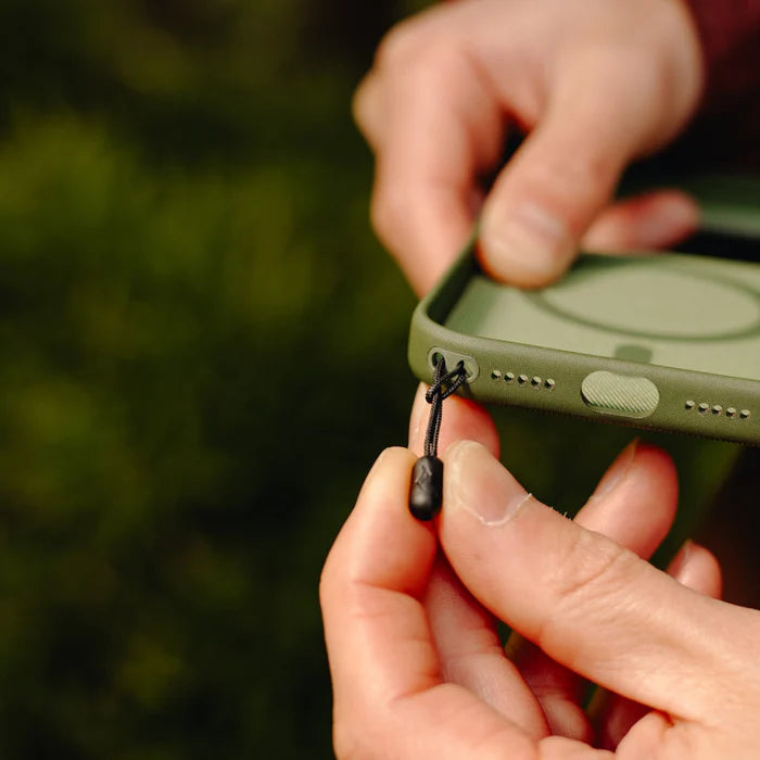close up shot of hands attaching peak design mobile straps microanchor to a green phone case.